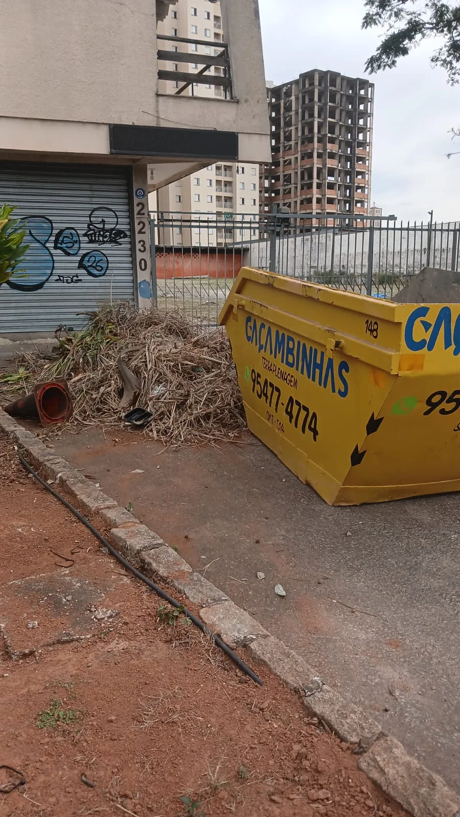 Caçamba amarela da Caçambinhas em frente a uma obra