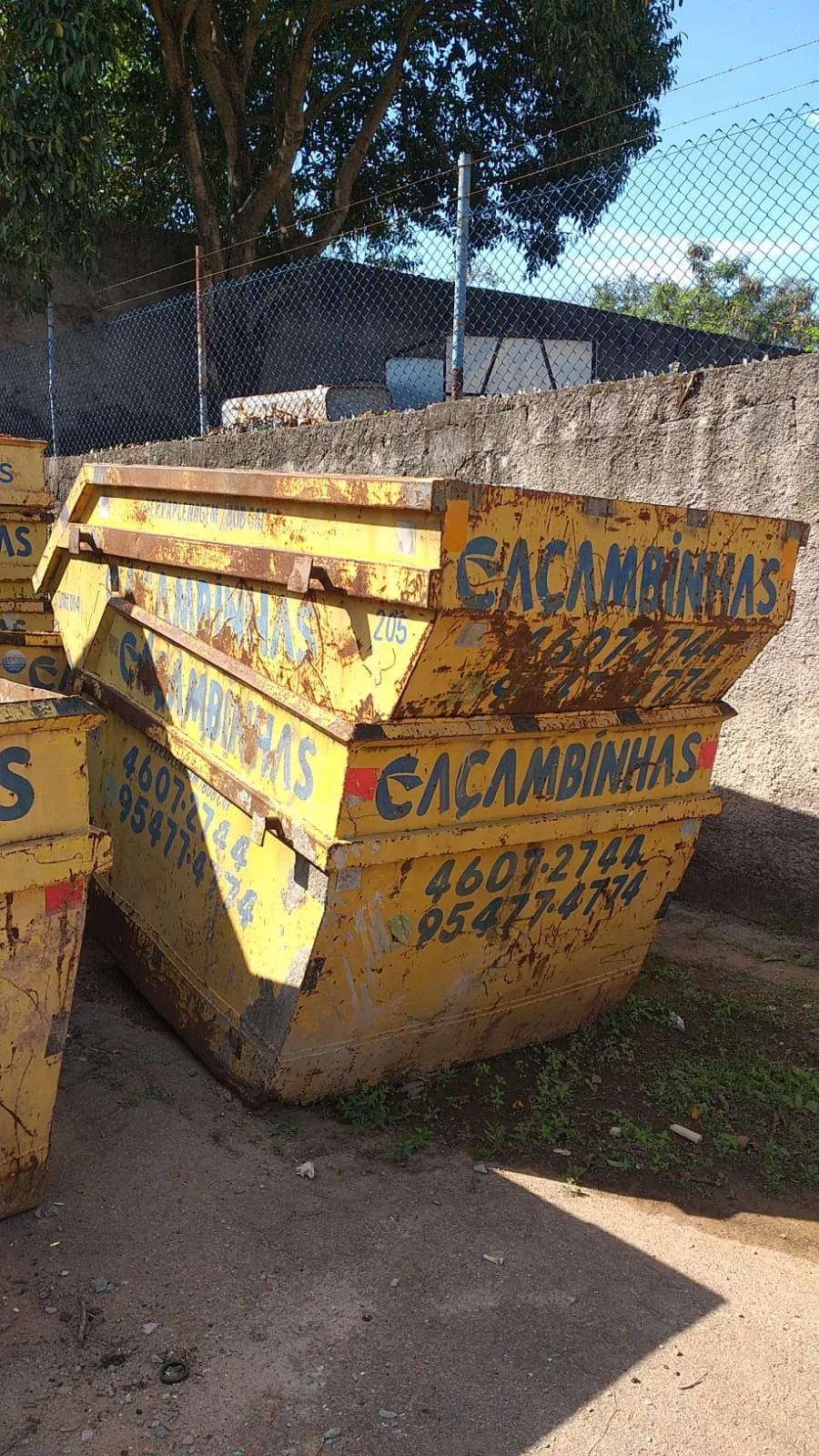 Caçambas amarelas empilhadas em área de operação
