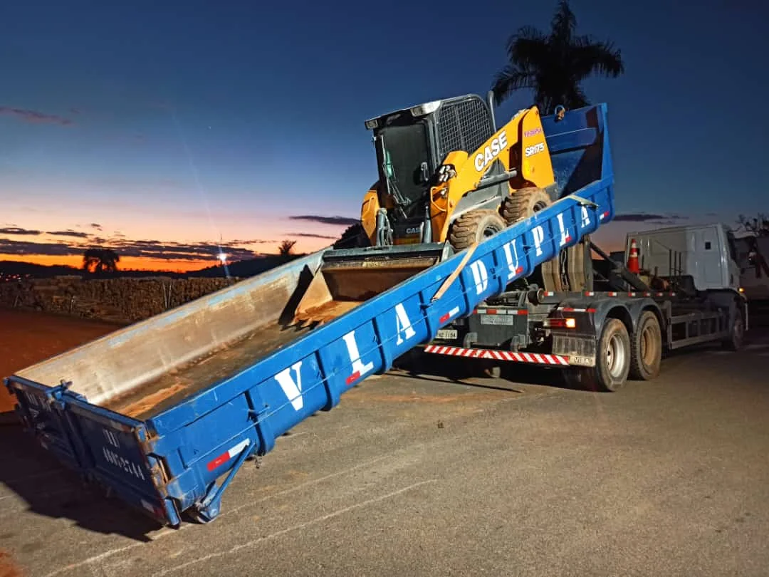 Caminhão azul da Via Dupla transportando equipamento ao entardecer